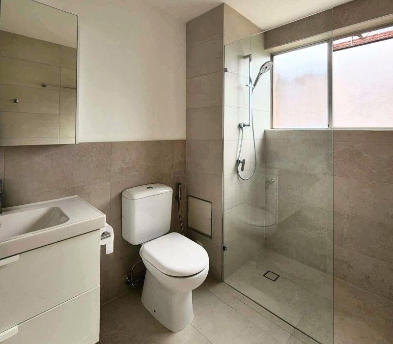 Modern bathroom with large neutral tiles and a wall-mounted mirror cabinet