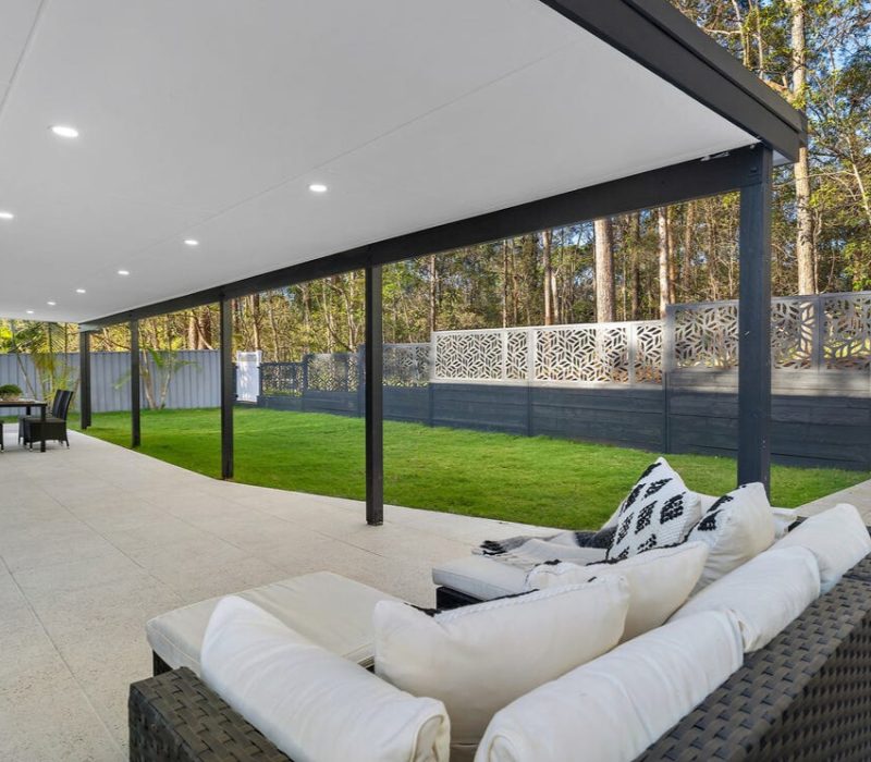 Covered outdoor patio with ceiling lights and green lawn