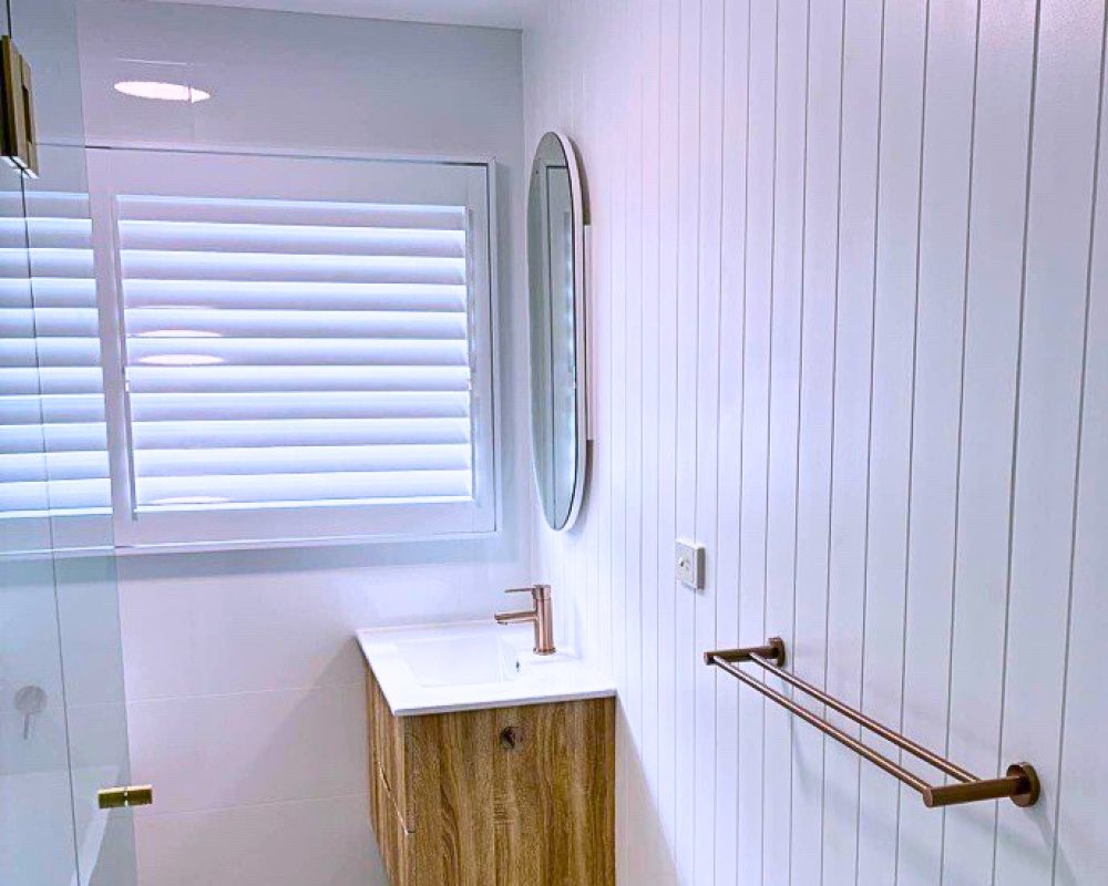Bathroom with timber floating vanity, round mirror, and white vertical wall panels