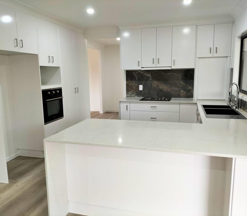 White kitchen with gas cooktop and marble-look splashback