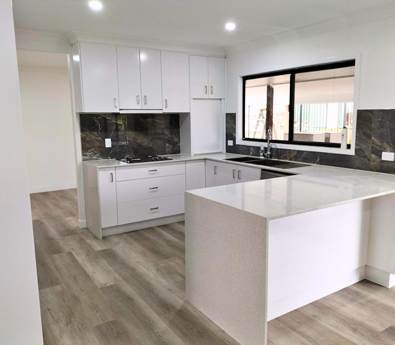 Bright corner kitchen with dual sink and timber-look floors