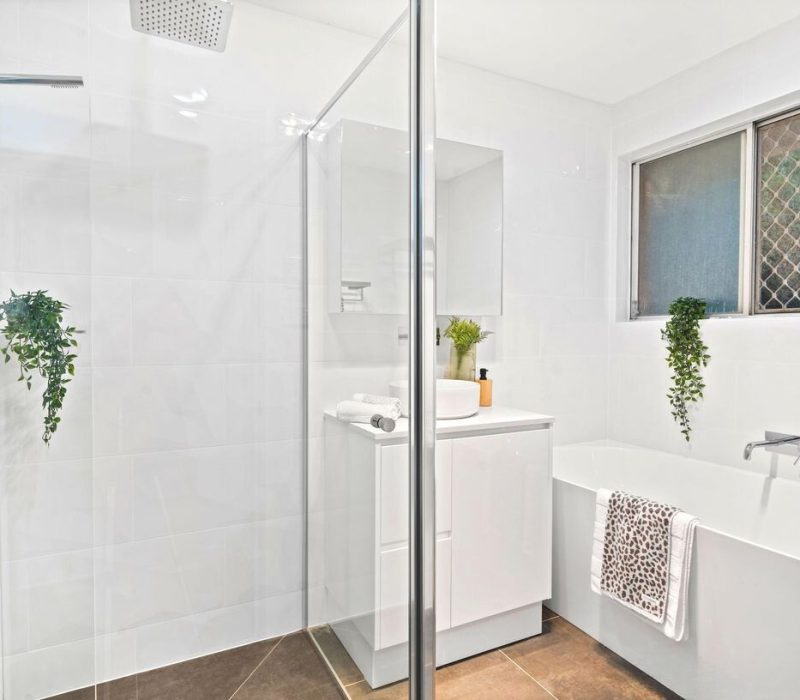 Clean white bathroom with tub, walk-in shower, and leafy green touches