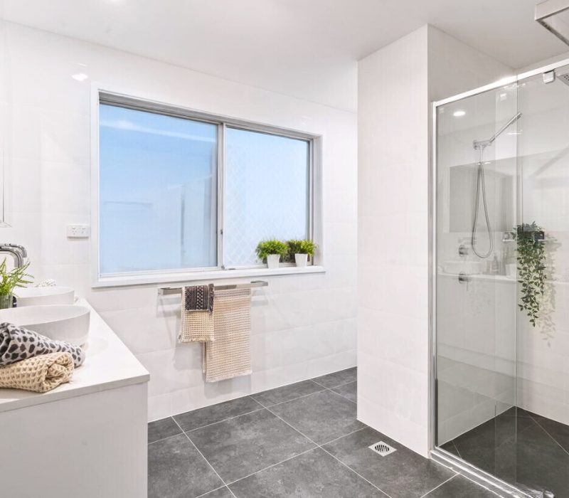 Bright white bathroom with walk-in shower and black floor tiles
