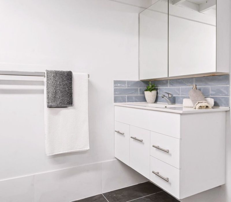 Minimal bathroom with floating vanity and blue subway tile splashback