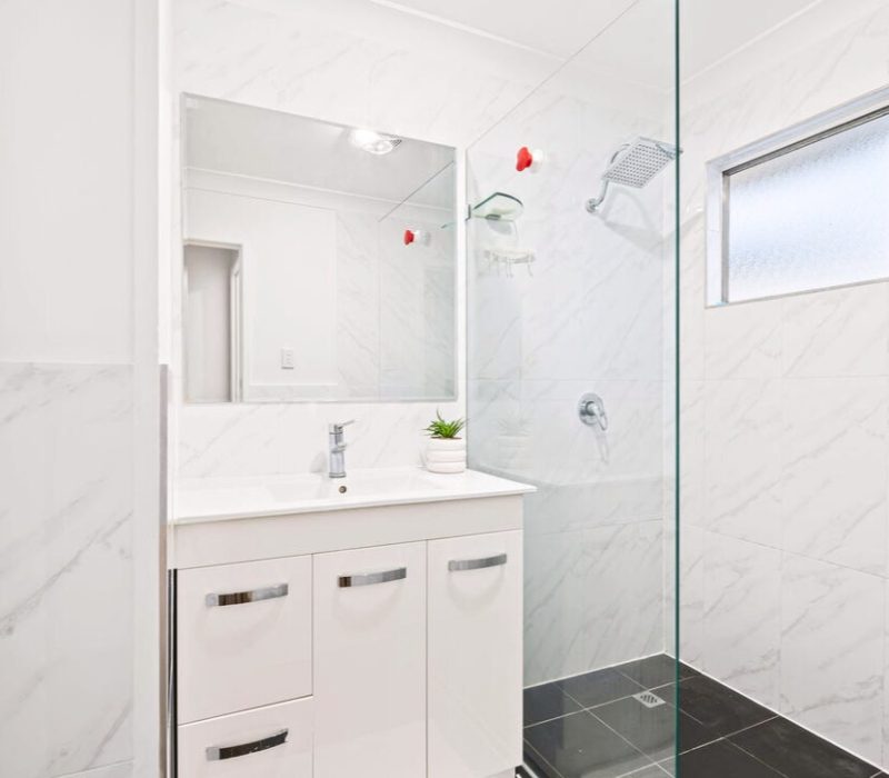 Modern white bathroom with marble-look walls and walk-in shower