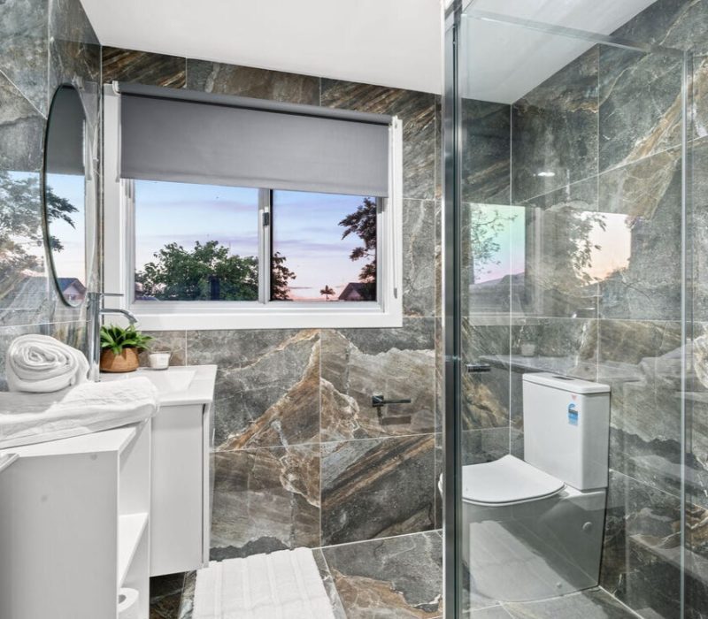 Compact bathroom with dramatic stone-look tiles and walk-in shower