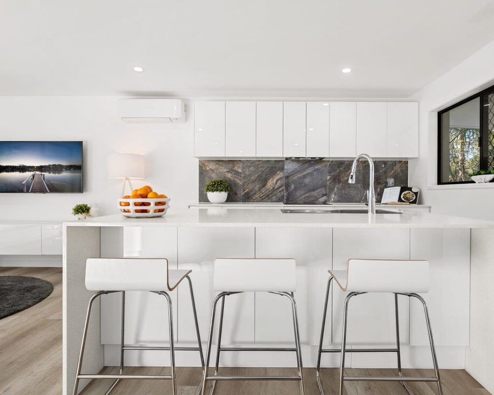 White kitchen with breakfast bar, tiled splashback and matching cabinetry