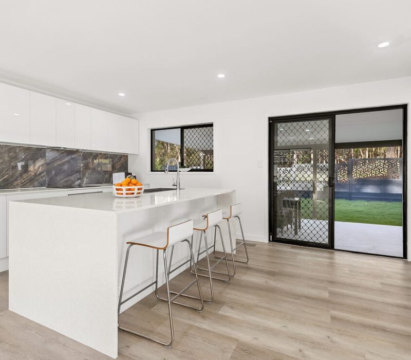 Modern white kitchen with stone splashback and large island bench