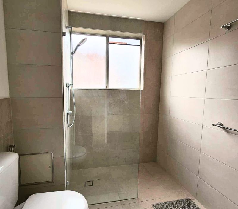 Spacious walk-in shower with full-height tiles and frosted glass window
