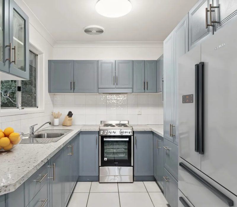 Compact kitchen with blue cabinetry and white tile splashback
